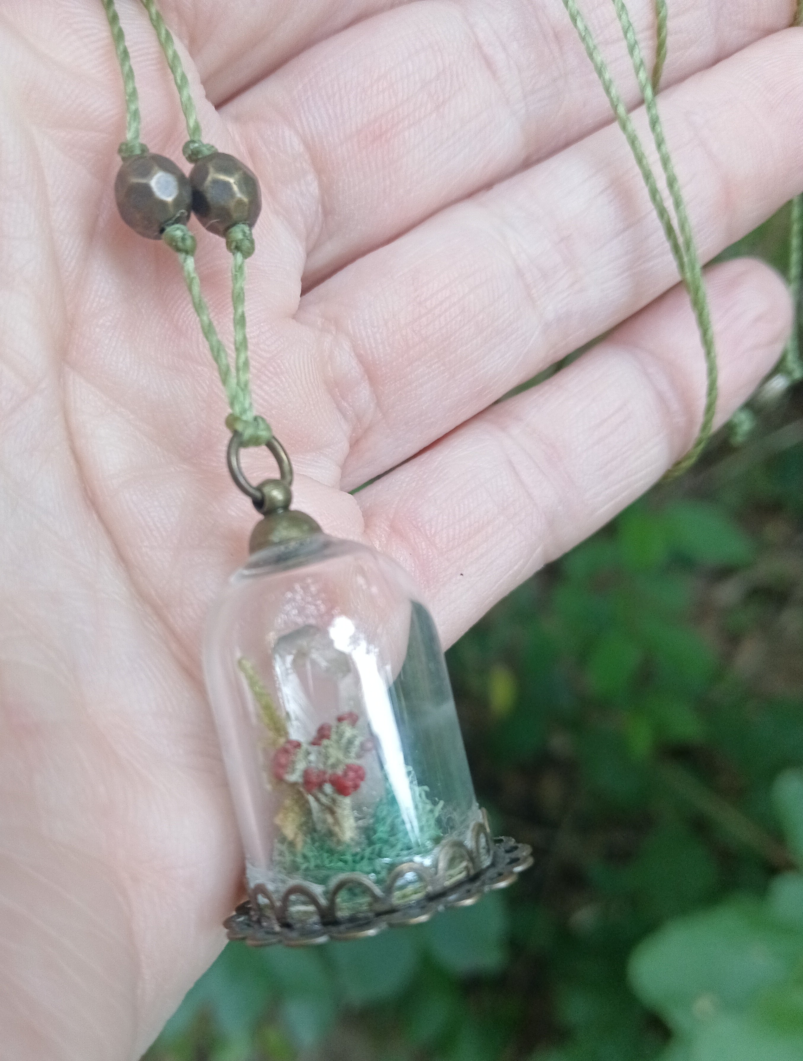 Glass cloche pendant with a quartz point and red berries in green moss