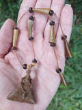 Cord-wrapped triangular bone pendant with horn spike and dark wood beads