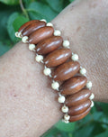 Woven bracelet of walnut oval beads edged with ivory seed beads, worn on a wrist