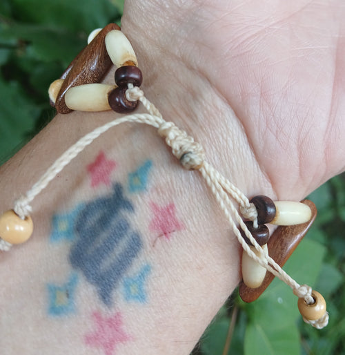 Adjustable bracelet with cream bone tube beads and wood cones on natural cord
