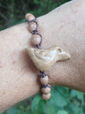 Macrame bracelet with a bird carved from picture jasper and pale wood beads